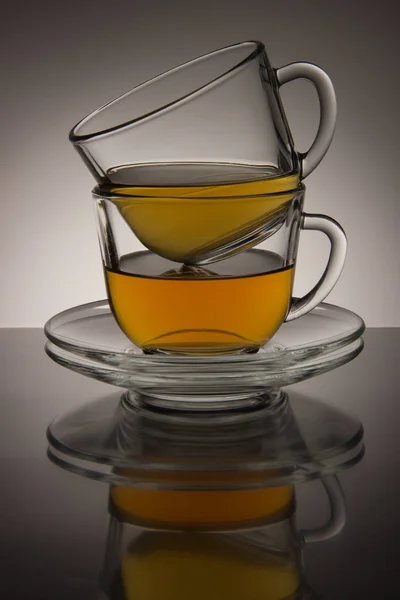 Zwei Glasbecher mit Tee und Untertasse auf schwarz-weißem Hintergrund — Stockfoto
