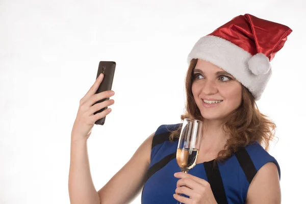 Menina em um chapéu de Natal vermelho com um telefone celular e um copo de c — Fotografia de Stock