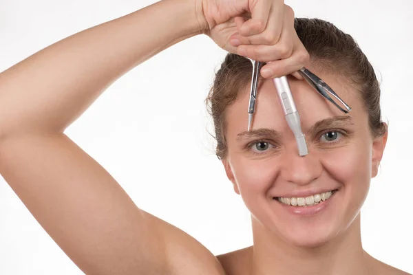 Young girl pulls out her eyebrows with tweezers metal on a white — Stock Photo, Image