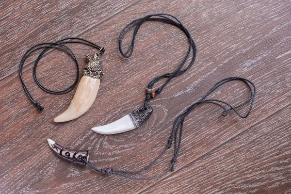 Big bear tooth and bone pendants carved from deer on a brown bac — Stock Photo, Image