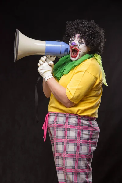 恐怖的小丑，在黑色背景上用扩音器大喊 — 图库照片
