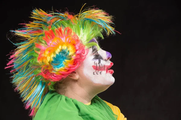 Enge clown met mohawk en een glimlach met een lolly over een zwarte b — Stockfoto