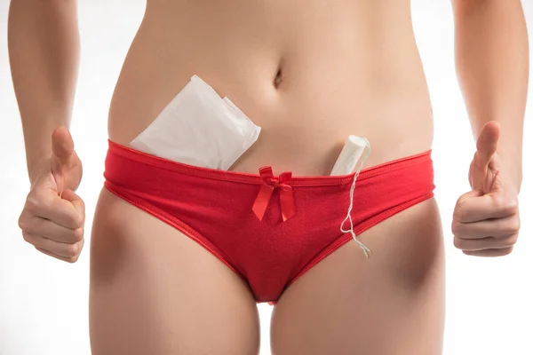 Girl in red shorts holding a hygienic tampons and pads during me — Stock Photo, Image