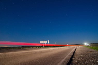 Alacakaranlık arabalar geçen farlar ile kırsal yol