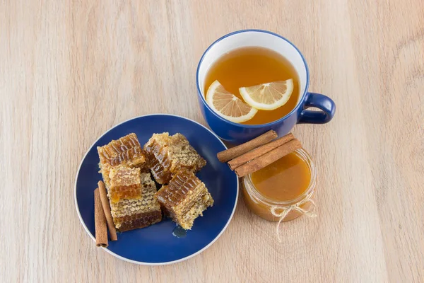 Trozos de panal de miel en una mesa con té, limón y canela —  Fotos de Stock