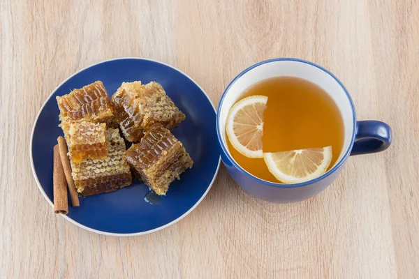Honigwabenstücke auf einem Tisch mit Tee, Zitrone und Zimt — Stockfoto