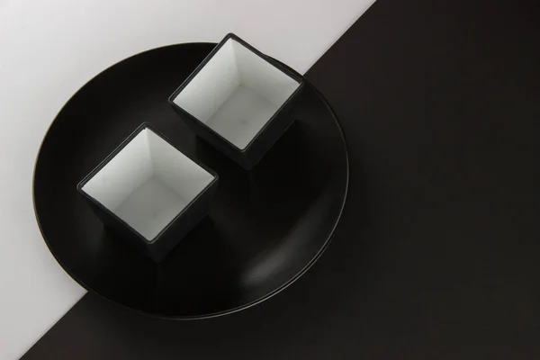 Um número de placas planas e copos em fundo preto e branco — Fotografia de Stock