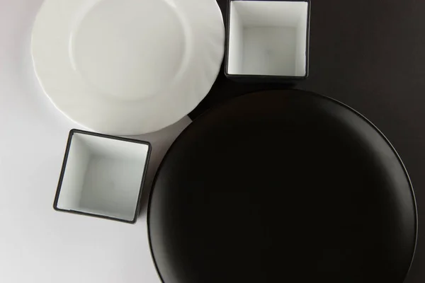Eine Reihe flacher Teller und Tassen auf schwarzem und weißem Hintergrund — Stockfoto