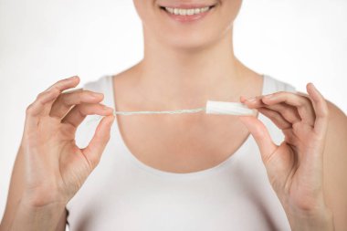 Genç bir kızın üzerinde bir başparmak gösterilmesini hijyenik tampon tutuyor