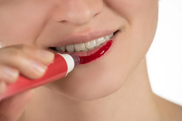 Uma menina bonita aplica um batom vermelho líquido persistente — Fotografia de Stock