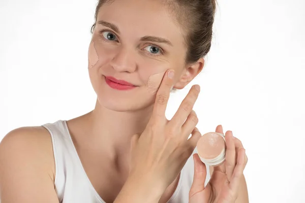 Young brunette woman applying makeup on skin foundation and smil — Stock Photo, Image