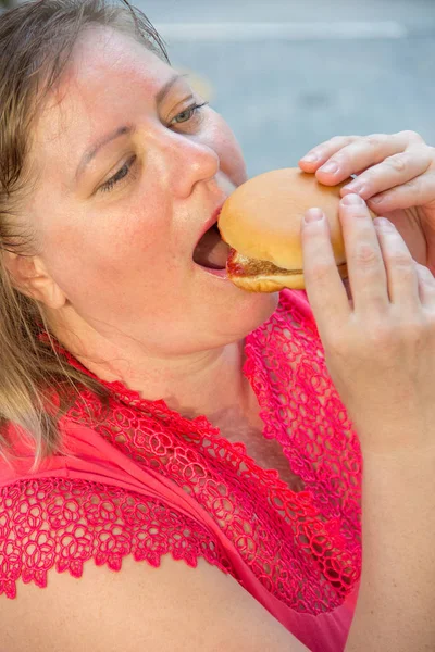 Silná žena jíst fast food hamburger a hranolky v kavárně — Stock fotografie