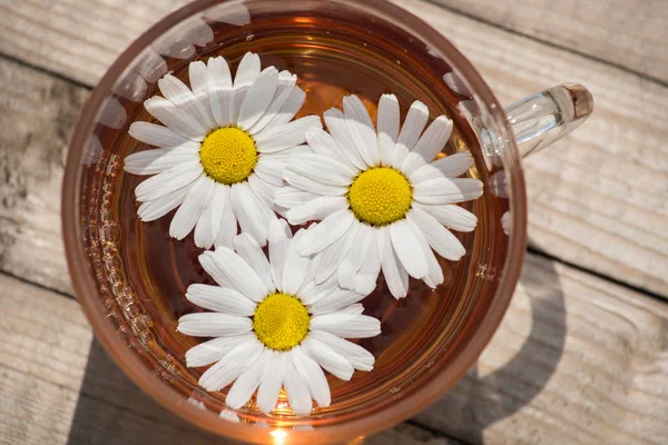 Kräutertee mit Kamille auf einem Holztisch an einem sonnigen Sommertag — Stockfoto