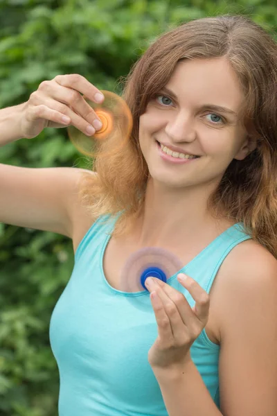 Young beautiful girl smiles and fools around with moving spinner — Stock Photo, Image