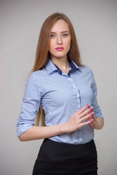 Junge schöne Geschäftsfrau im blauen Hemd steht mit verschränkten Armen da und denkt über einen grauen Hintergrund nach — Stockfoto