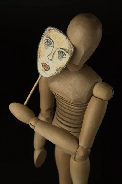 Fából készült baba zsanérok maszk tart a kezében, és magában foglalja az arcát — Stock Fotó