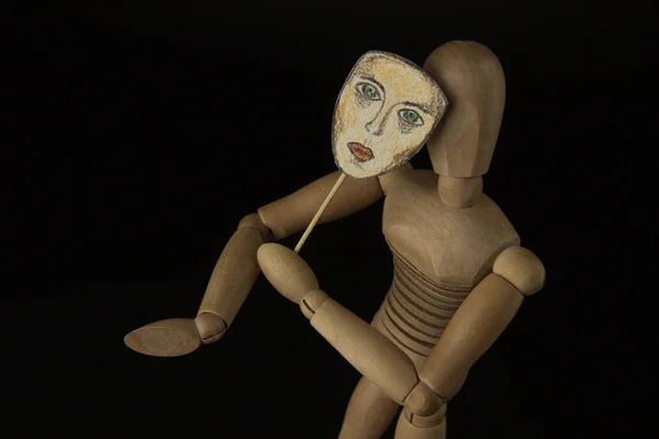 Ξύλινη κούκλα στις αρθρώσεις κατέχει μια μάσκα στα χέρια και να καλύπτει το πρόσωπό της — Φωτογραφία Αρχείου
