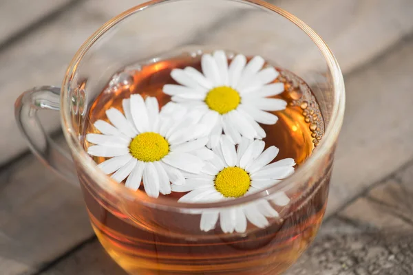 Bir yaz güneşli mo üzerinde ahşap bir masa üzerinde papatya ile bitkisel çay