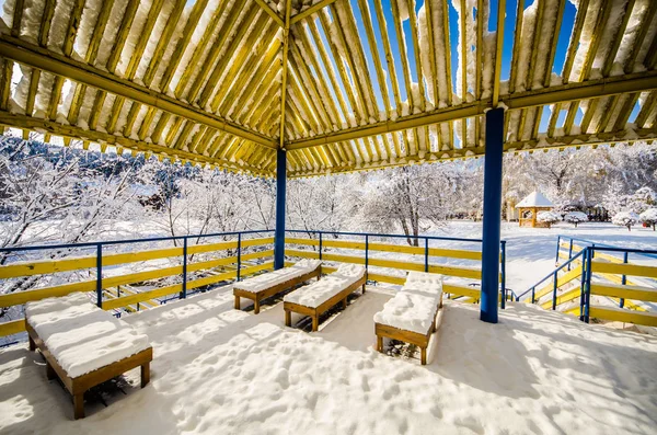 Un belvédère en bois dans un parc dans la neige et le ciel bleu — Photo