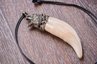 Geyik kahverengi bir arka plan üzerinde gelen büyük ayı diş ve kemik kolye oyulmuş