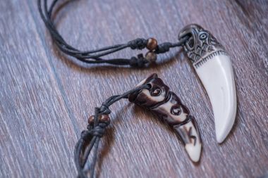 Geyik kahverengi bir arka plan üzerinde gelen büyük ayı diş ve kemik kolye oyulmuş