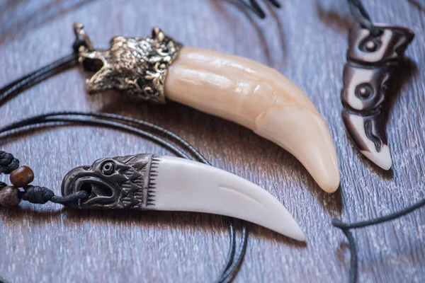 Geyik kahverengi bir arka plan üzerinde gelen büyük ayı diş ve kemik kolye oyulmuş