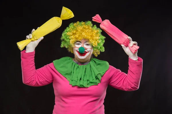 Funny clown with hair and a cheerful make-up holding a gift — Stock Photo, Image