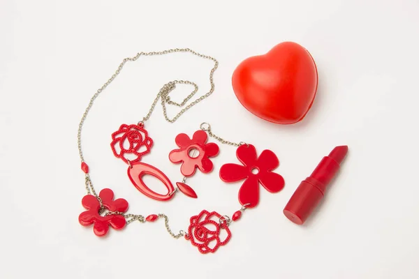 Red lipstick, heart and necklace with flowers on a white backgro Stock Photo