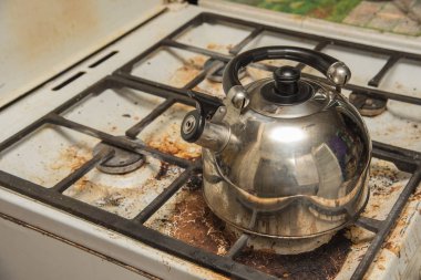 Bir kirli gaz soba ve metal bir su ısıtıcısı üzerinde durmak