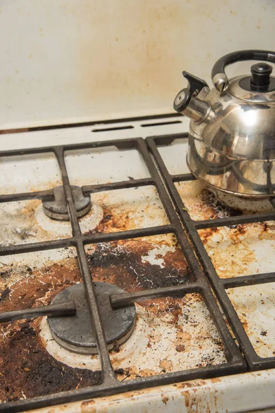 Bir kirli gaz soba ve metal bir su ısıtıcısı üzerinde durmak