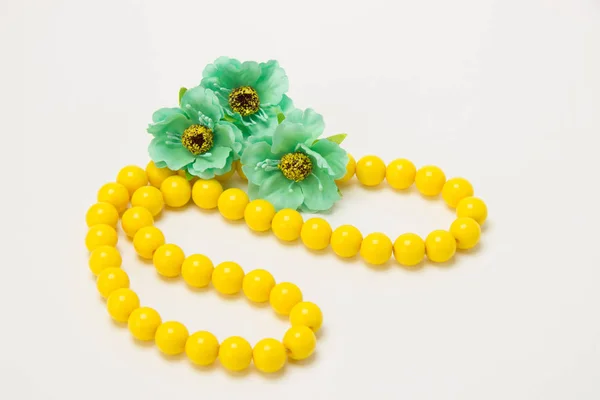 Collier de perles jaunes avec des fleurs vertes sur un fond blanc — Photo