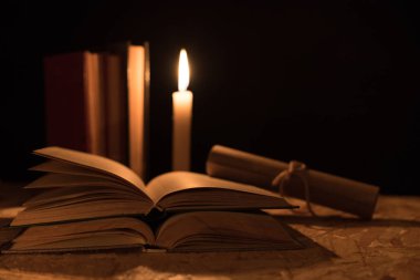 Büyülü bir top, bir parşömen, bir mum ve gecenin karanlığında eski bir kitap.