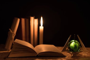 Büyülü bir top, bir parşömen, bir mum ve gecenin karanlığında eski bir kitap.