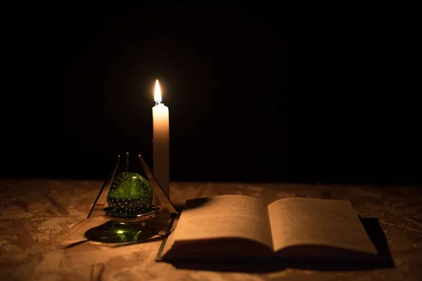 Una bola mágica, un pergamino, una vela y un viejo libro en la oscuridad de la noche —  Fotos de Stock