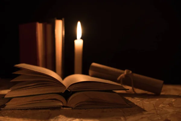 Eine magische Kugel, eine Schriftrolle, eine Kerze und ein altes Buch in der Dunkelheit der Nacht — Stockfoto