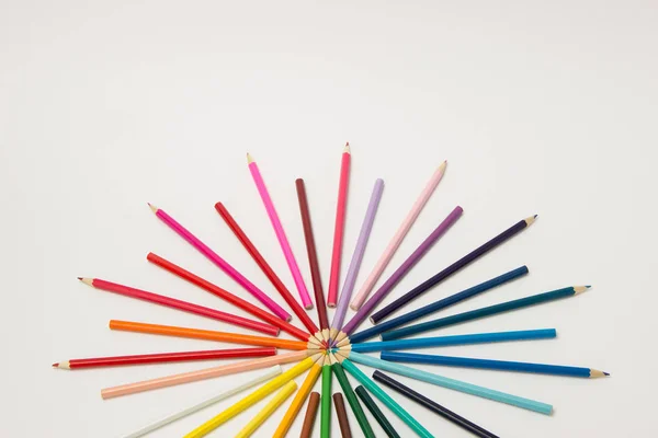 A group of pencils folded in rainbow colors in a circle on a whi — Stock Photo, Image