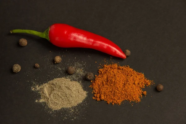 Hot pepper and spices on a black background — Stock Photo, Image