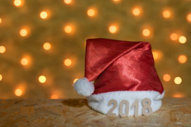 2018 arka planda bir yılbaşı Garland bulanık altın ışıklı bir masaya rakamlar ile kırmızı bere