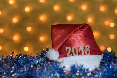 Kırmızı bere ve 2018 arka planda bir yılbaşı Garland bulanık altın ışıklı bir masaya rakamlar ile mavi gelin teli