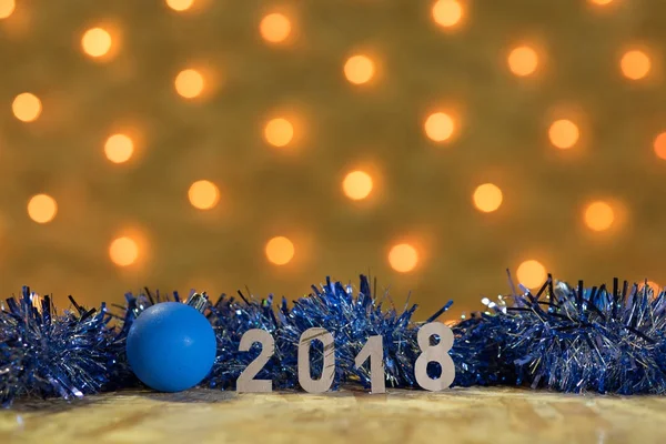 青い見掛け倒しと黄金色のライトと新年のガーランドの背景上のテーブルで 2018年の数字を持つボール — ストック写真