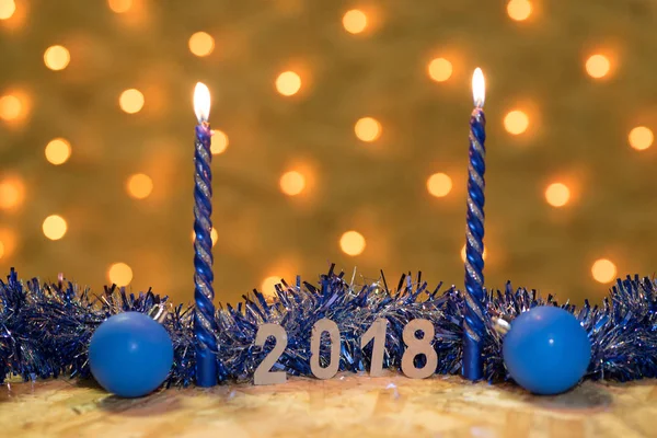 Синя мішура, м'яч і свічки з фігурами 2018 року на столі на фоні новорічної гірлянди з золотими вогнями — стокове фото