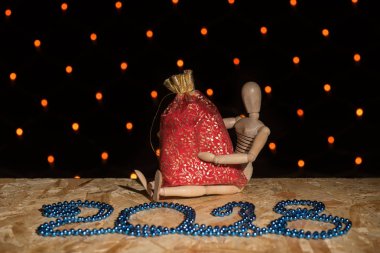 Ahşap oyuncak kukla oturur ve bir kırmızı yılbaşı çantası ile tutan bir 