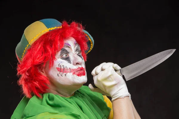 Enge clown met een afschuwelijk make-up lacht en met messen in ha — Stockfoto