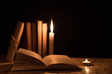 Eski kitaplar, yanan bir mum ve bir kaydırma üzerinde ahşap bir masa üzerinde bir 