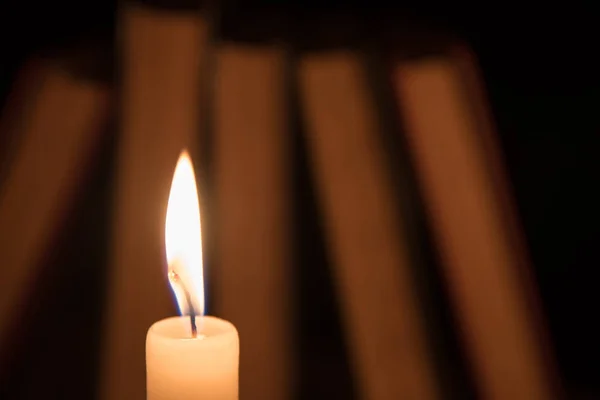 Libros antiguos y una vela encendida en una mesa de madera en una noche —  Fotos de Stock