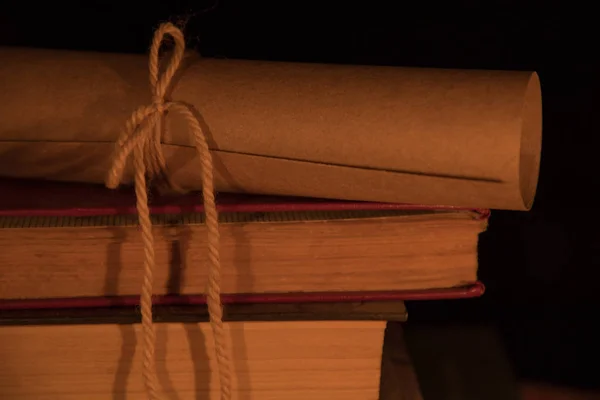 Eski kitaplar ve bir gecede ahşap bir masa üzerinde bir kaydırma — Stok fotoğraf