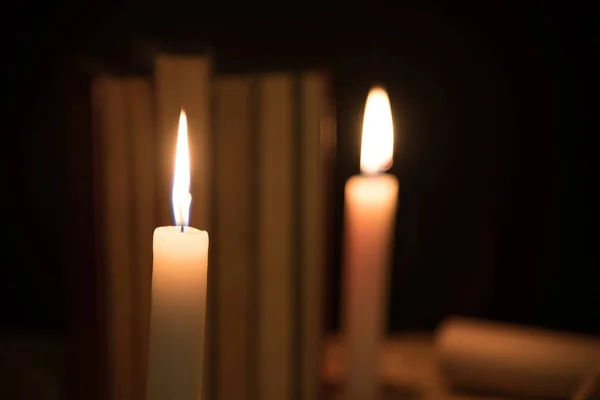 Oude boeken en brandende kaars op een houten tafel op een nacht — Stockfoto