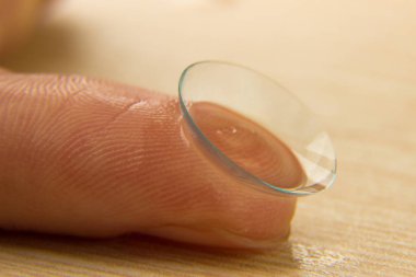 Kontakt lensler için ahşap bir masa üzerinde bir insan parmağı gözünü