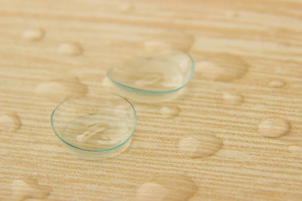 Lentes de contato de olhos com baixas de solução em uma mesa de madeira — Fotografia de Stock