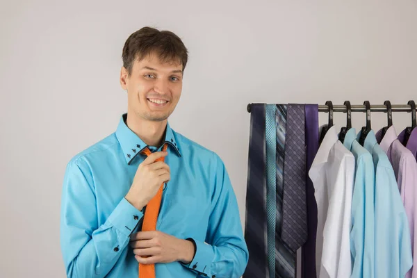 Giovane uomo sexy sceglie una camicia da una varietà di camicie appese — Foto Stock